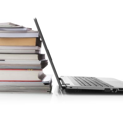 Open laptop screen leaning against a stack of books